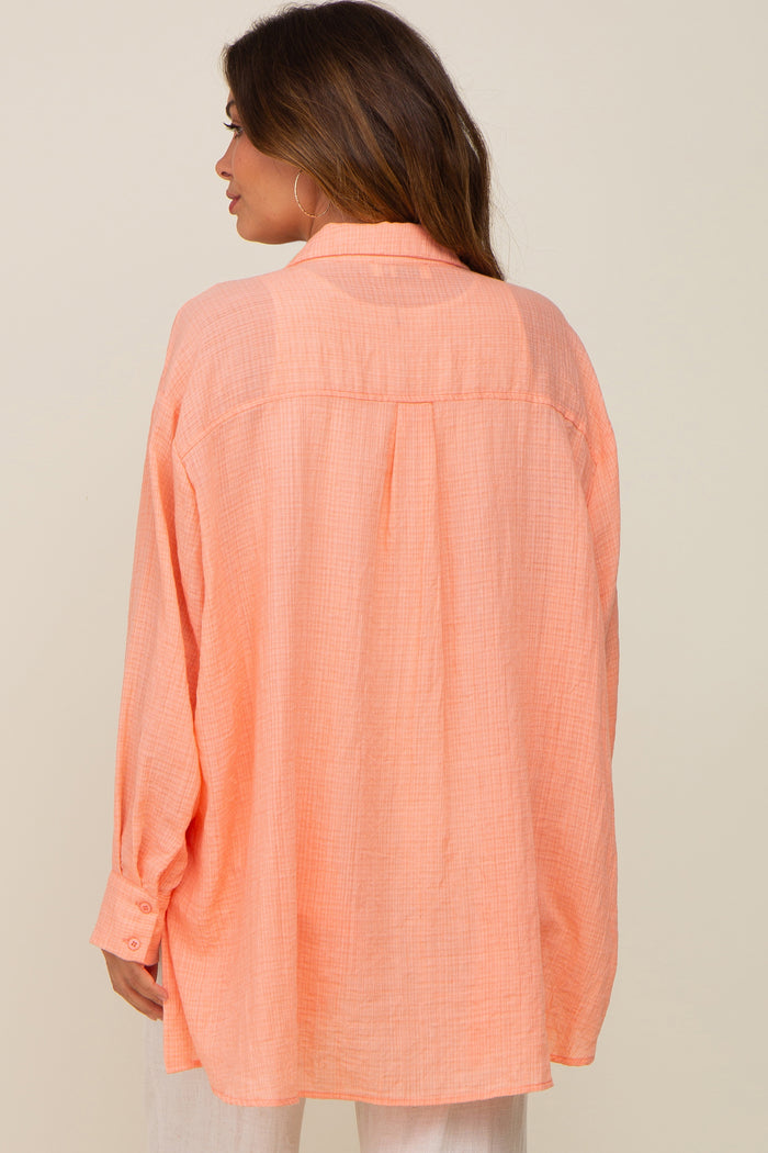 Back view of a woman wearing an oversized peach button-down linen shirt with long sleeves and a collar