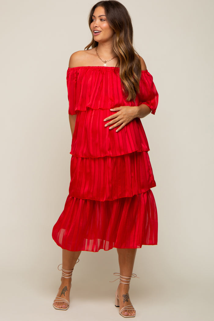 woman wearing a red tiered off-the-shoulder maternity dress and holding her baby bump