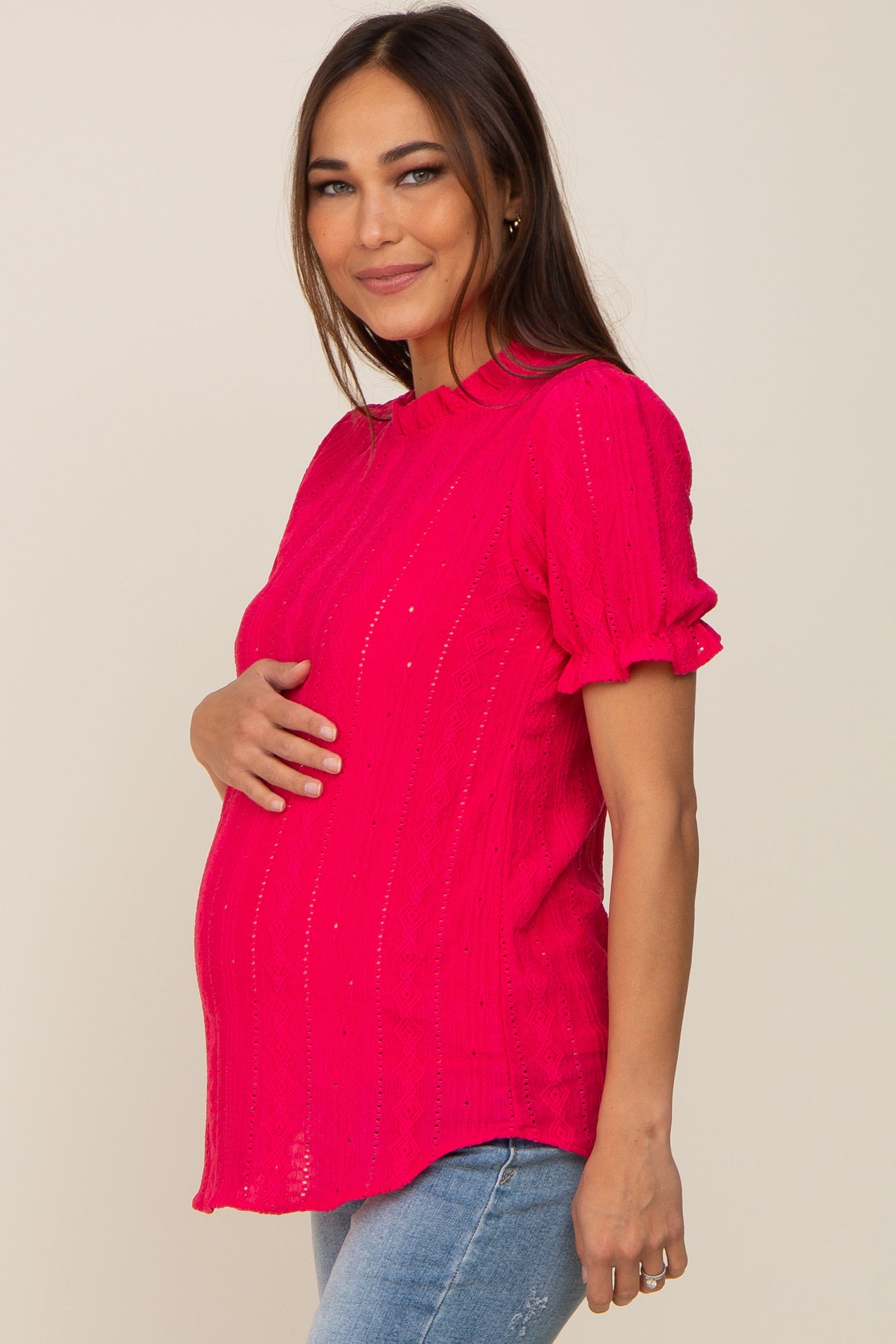 woman wearing a bright pink short sleeve maternity top and holding her baby bump