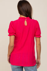 woman wearing a hot pink maternity top with puff sleeves and a keyhole back detail
