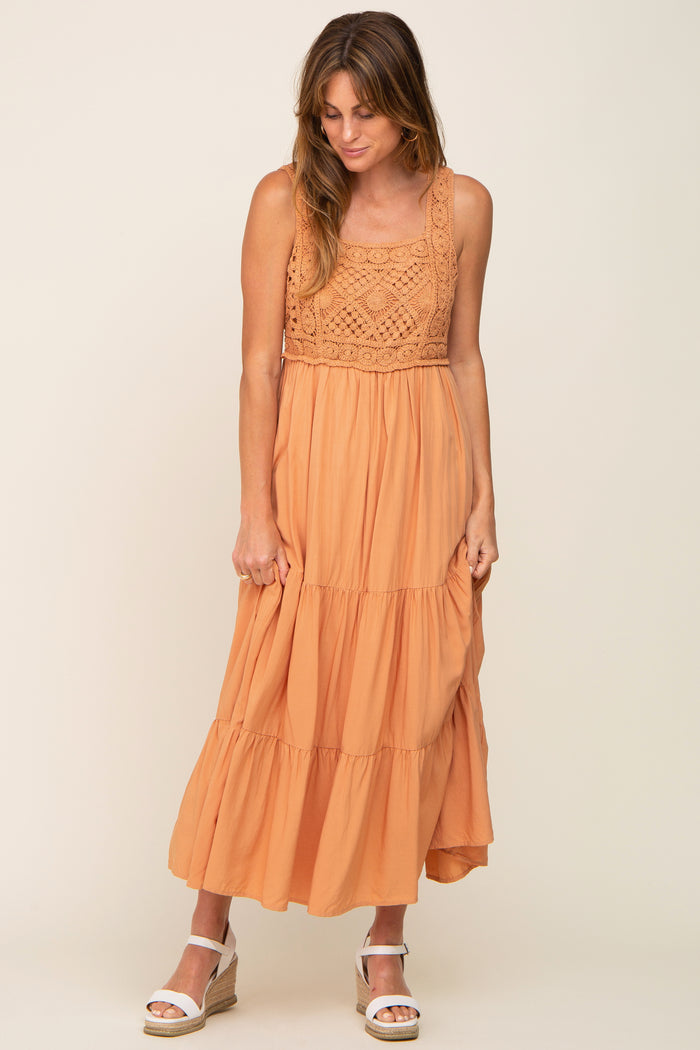 woman wearing an orange sleeveless maxi dress with a crochet bodice and tiered skirt