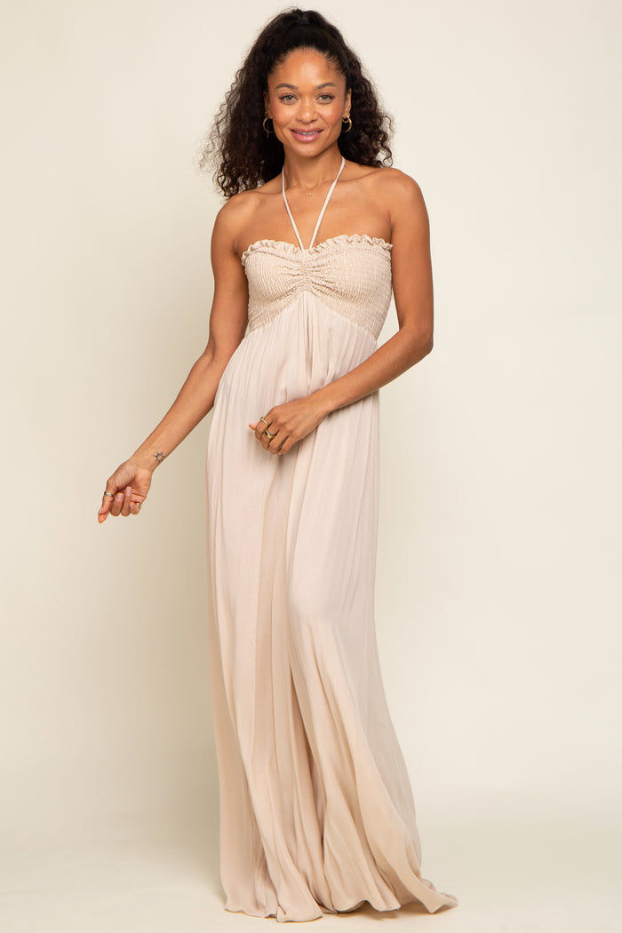 woman wearing a strapless nude-colored maxi dress with gathered detailing around the bust and flowing skirt