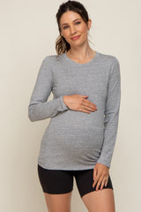 woman wearing a gray long sleeve maternity top and holding her baby bump, paired with black shorts
