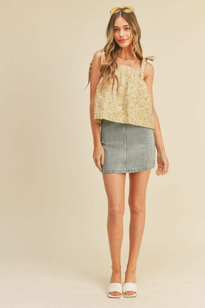 woman wearing yellow floral tie-shoulder top and denim mini skirt with white slide sandals