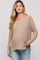 woman wearing a beige knitted maternity sweater with a v-neck and relaxed fit, styled with light blue jeans