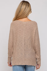 woman wearing a beige loosely knit maternity sweater with long sleeves, viewed from the back