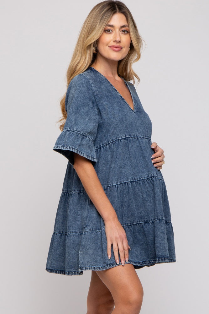 woman wearing a tiered dark denim maternity dress and holding her baby bump