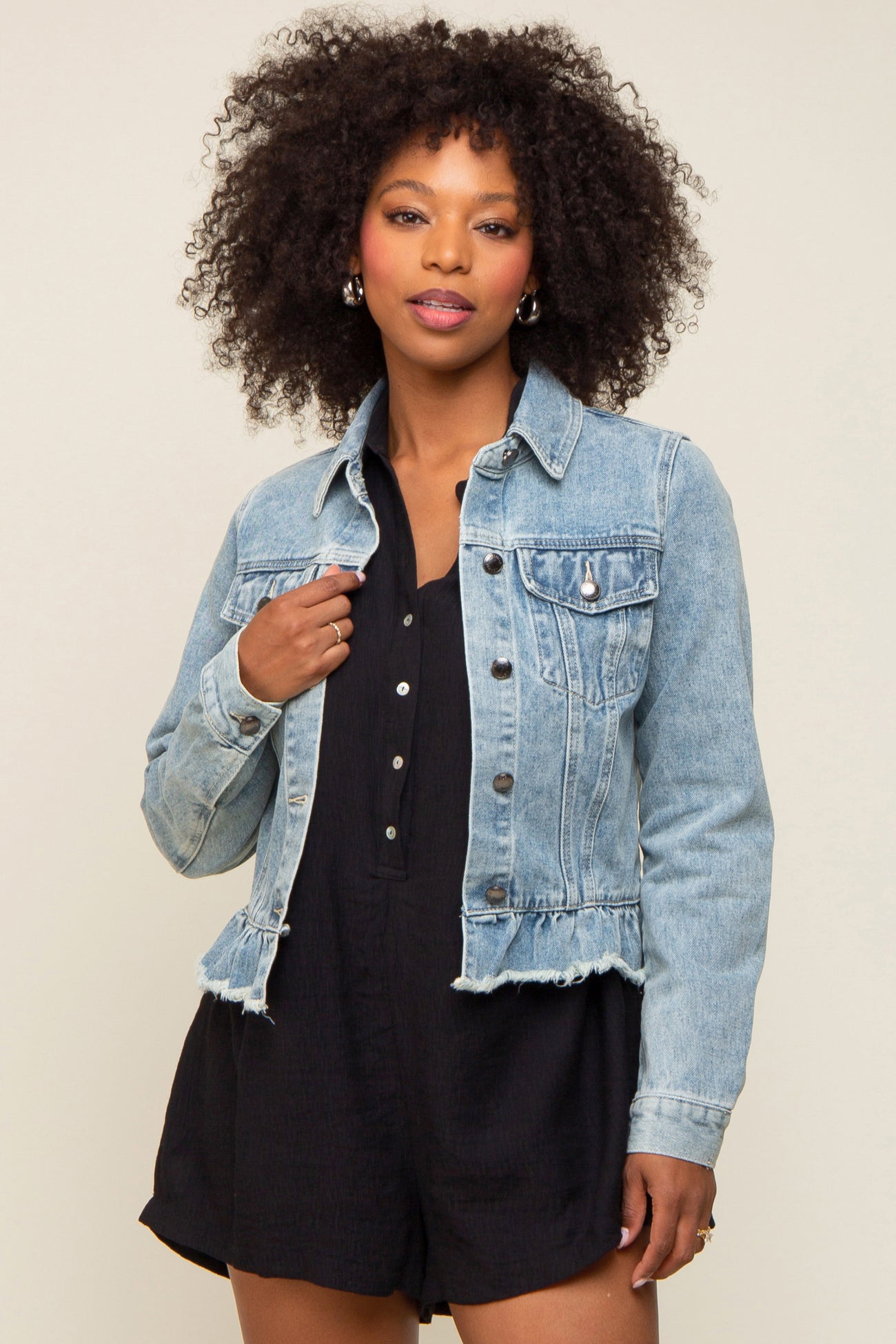 woman wearing a light blue cropped denim jacket over a black playsuit