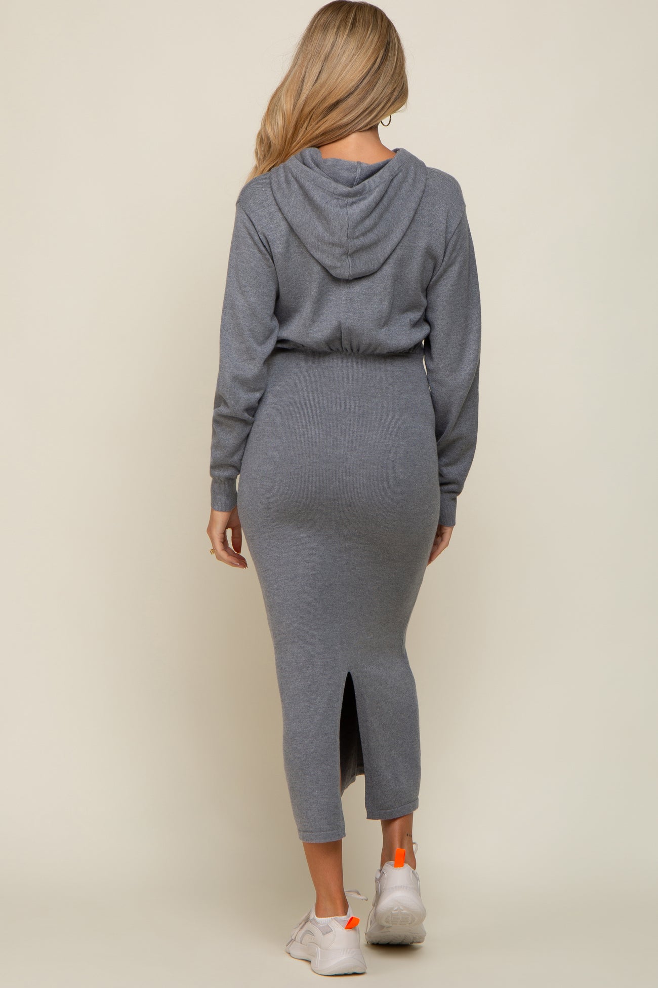 woman wearing a grey maternity dress with a fitted design, hood, and back slit, showcasing her baby bump