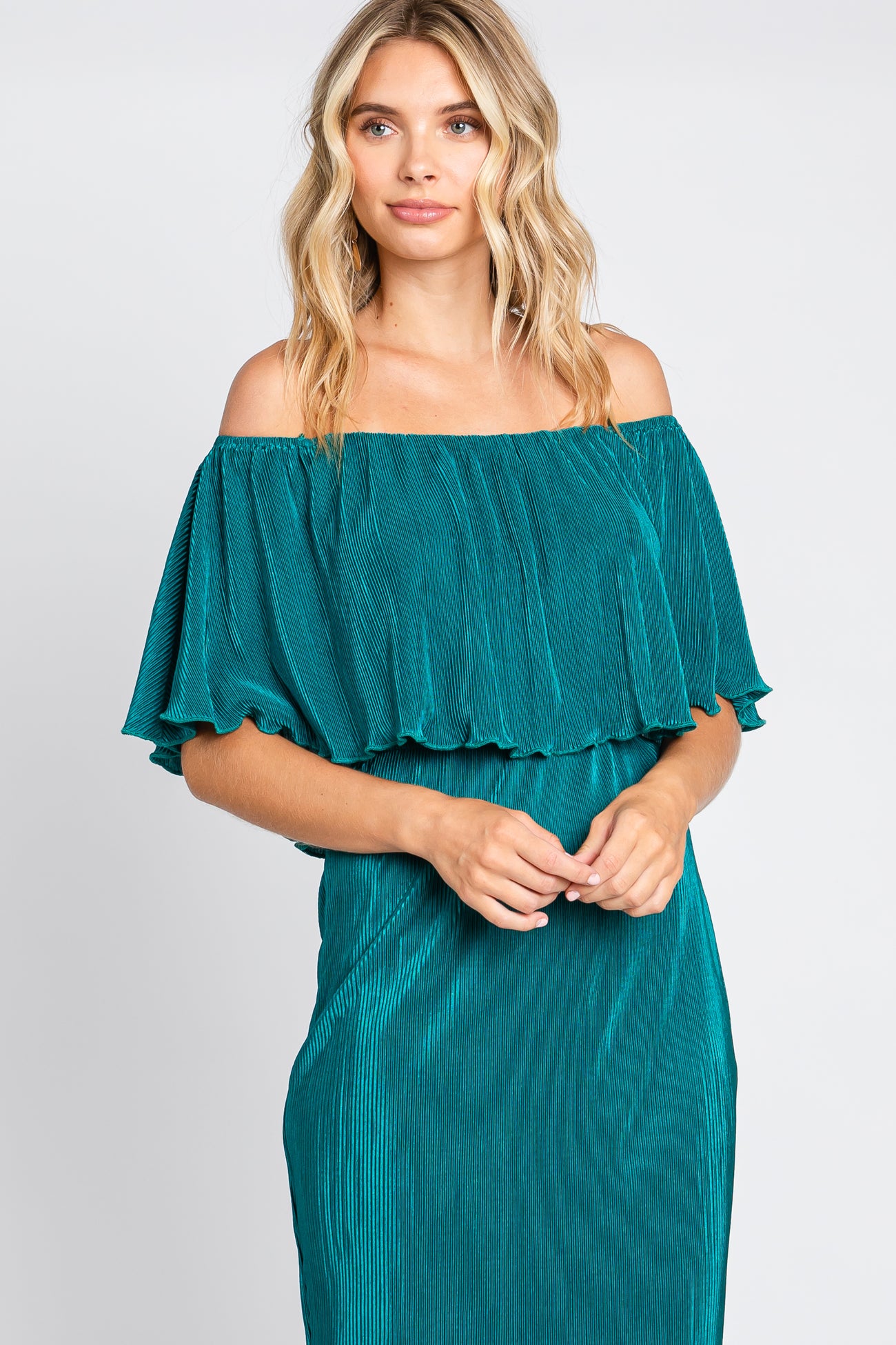 woman wearing a teal off-the-shoulder pleated ruffle dress against a white background