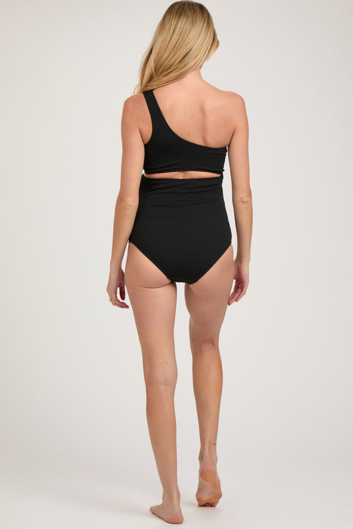 woman wearing a black one-shoulder maternity swimsuit with a cutout detail on the back