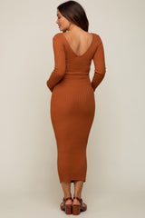 woman wearing a rust ribbed maternity dress with a deep V-back and long sleeves, showing her baby bump
