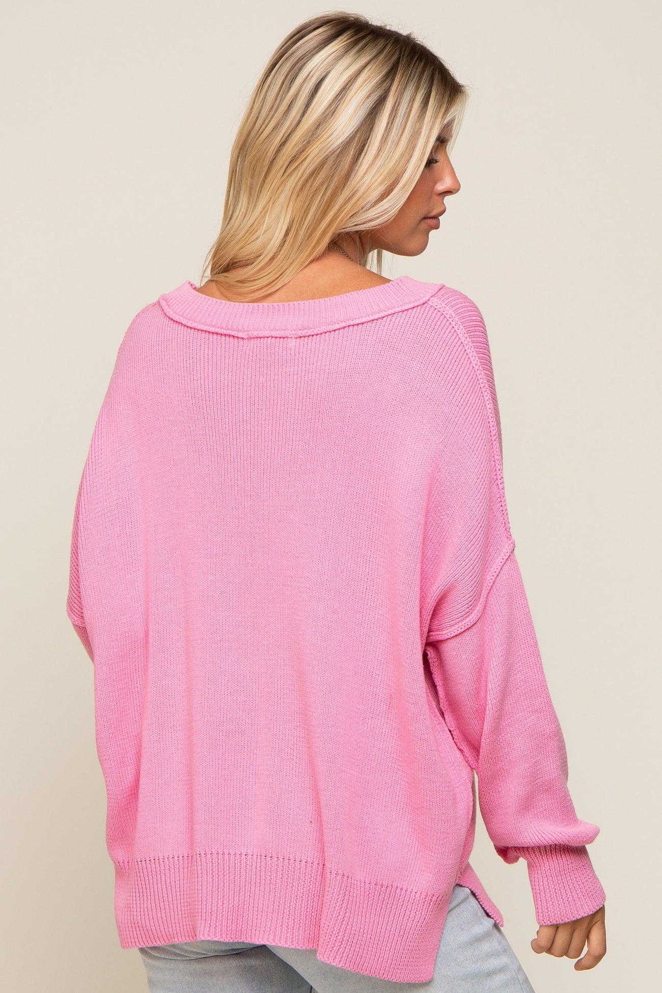 woman wearing a loose-fitting pink oversized sweater with a wide neckline and long sleeves