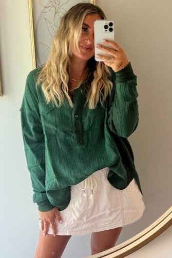 woman wearing a green long sleeve button-up top with a relaxed fit and white drawstring shorts