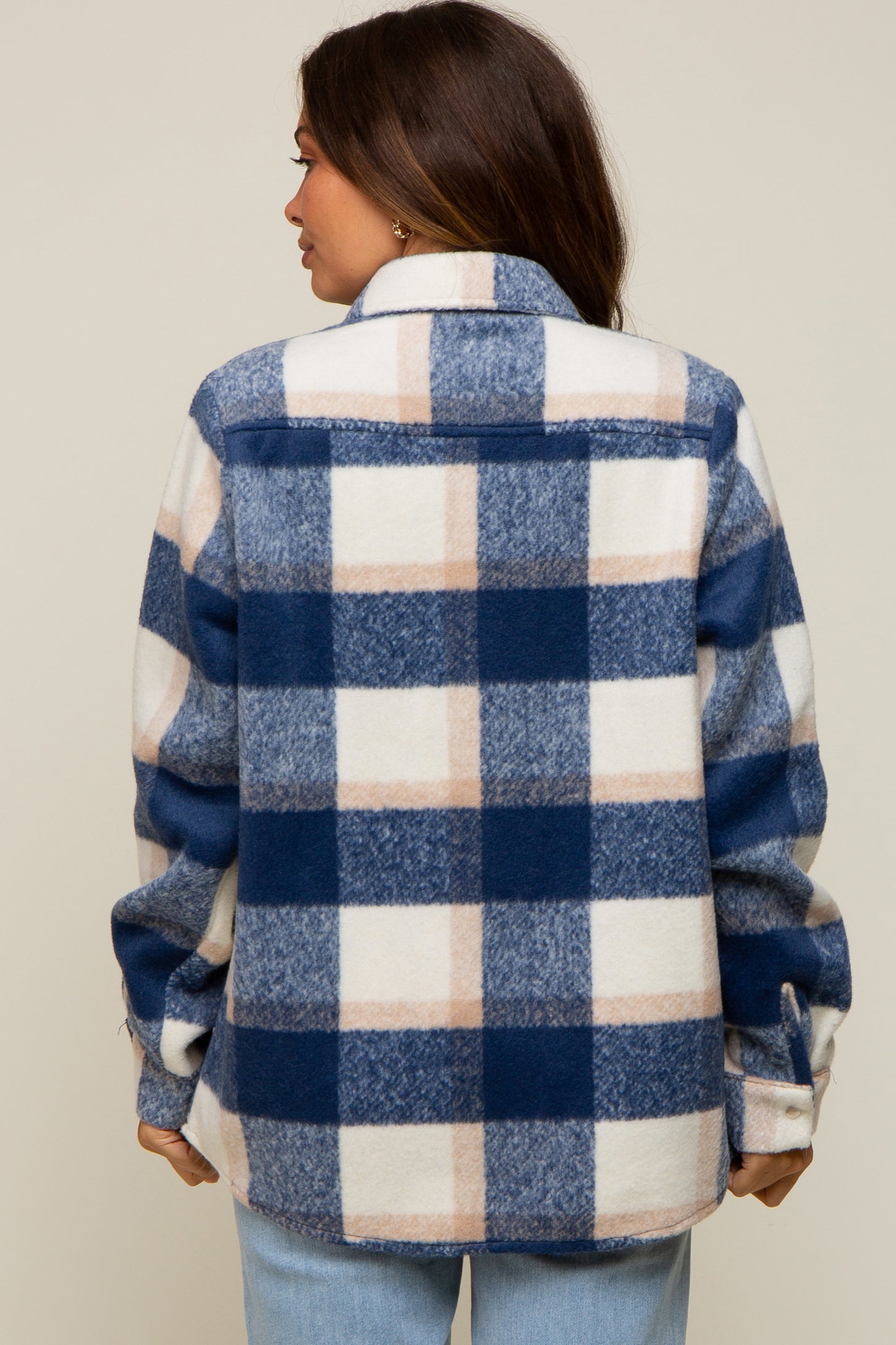woman wearing a navy and cream checkered maternity shacket, styled casually from the back