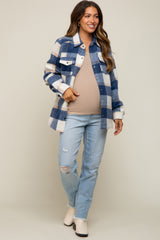 woman wearing a blue and white checkered maternity shirt jacket over a beige top and distressed jeans, showing her baby bump