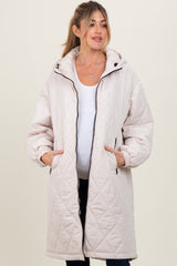 woman wearing a light beige quilted maternity coat with a hood and pockets, baby bump visible