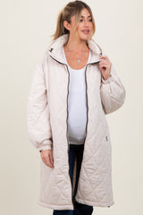 woman wearing a light beige maternity quilted coat and showing her baby bump