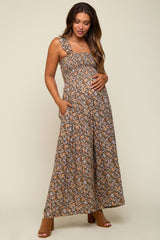 woman wearing a floral print maternity maxi dress with adjustable straps and pockets, holding her baby bump