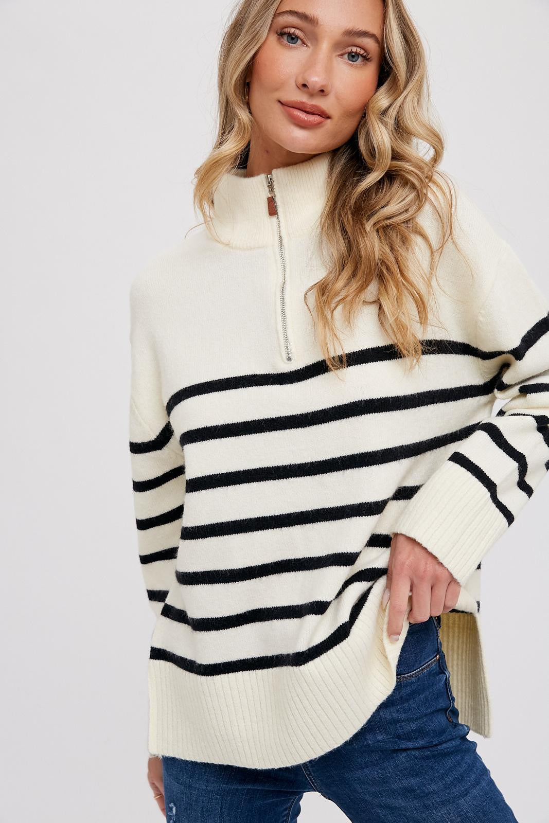 woman wearing a cream and black striped quarter-zip sweater with a relaxed fit and side slits