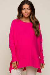 woman wearing a bright pink oversized maternity sweater with long sleeves and a high-low hemline