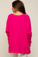 back view of a woman wearing a bright pink oversized knit sweater with a crew neck and ribbed hem