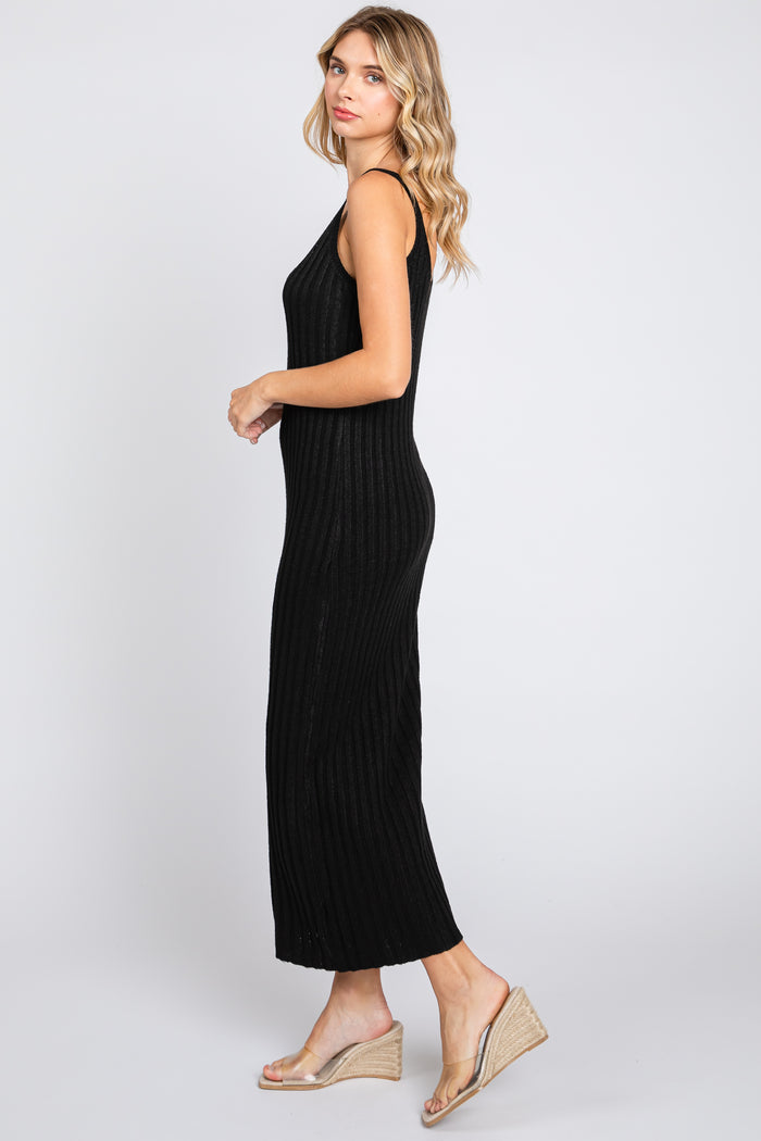 woman wearing a black ribbed maxi dress with a fitted silhouette and side slits, styled with clear wedge sandals
