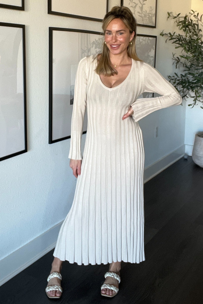 woman wearing a cream colored ribbed long sleeve maxi dress in a modern setting