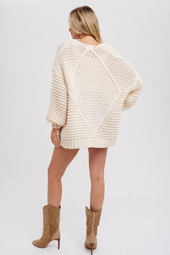 woman wearing an oversized cream colored sweater with textured knit and drop shoulders, showing the back view