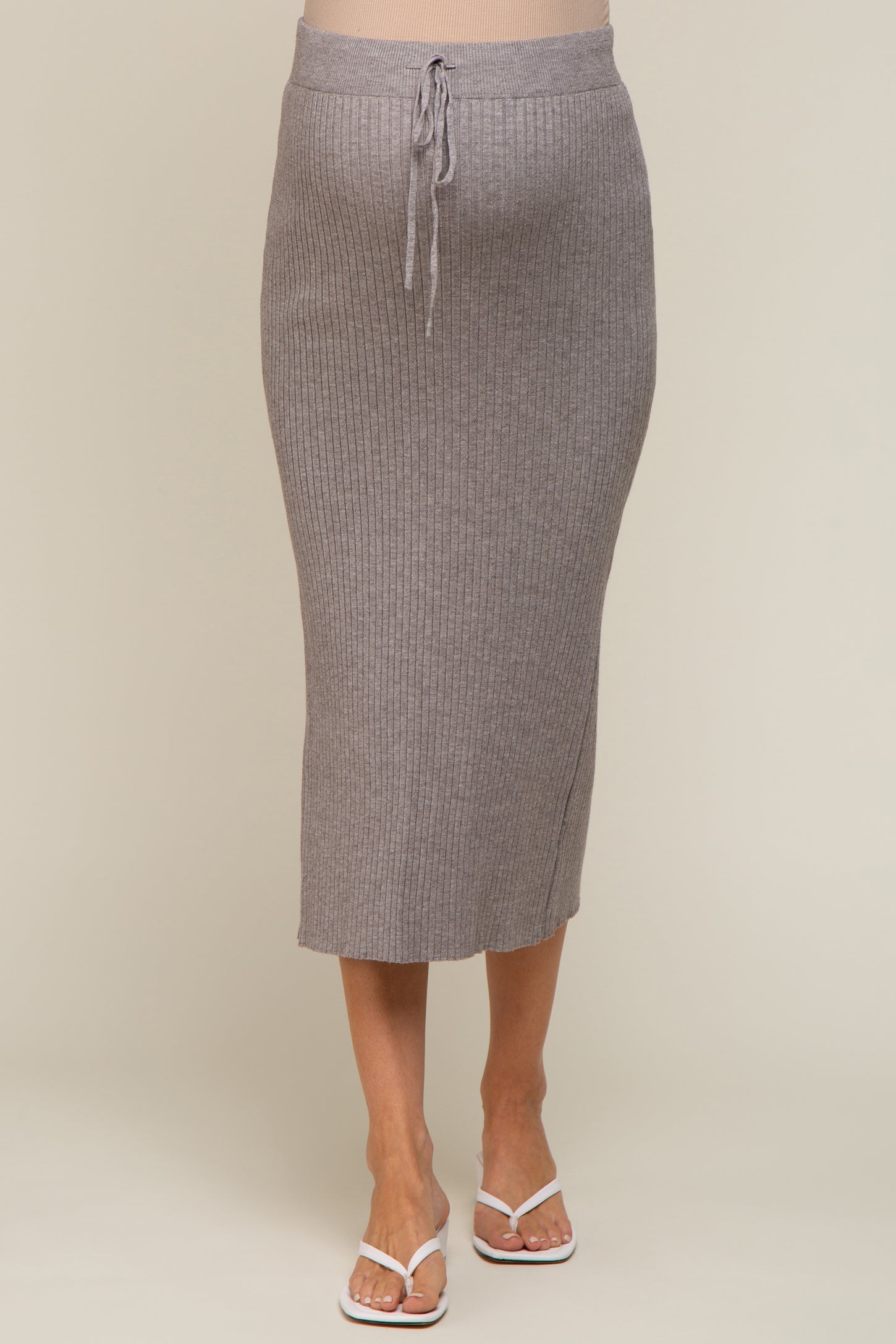 woman wearing a grey ribbed maternity midi skirt with drawstring waist and white flip flops