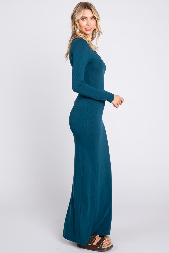 woman wearing a long teal maxi dress with long sleeves, posed sideways with a smooth silhouette