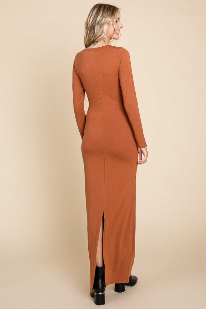 woman wearing a rust long sleeve maxi dress with a back slit and fitted silhouette