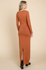 woman wearing a rust long sleeve maxi dress with a back slit and fitted silhouette