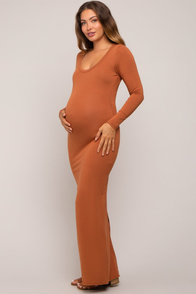 woman wearing a rust long sleeve maternity dress showcasing her baby bump