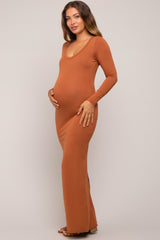 woman wearing a rust long sleeve maternity dress showcasing her baby bump