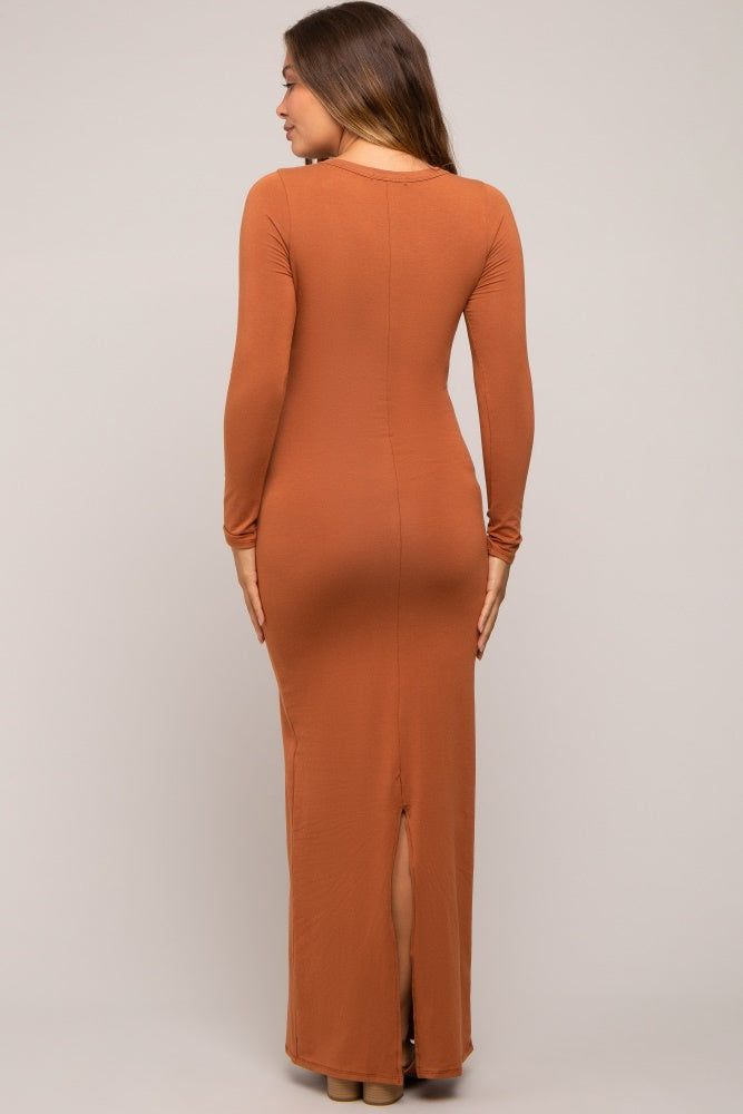 woman wearing a rust long sleeve maternity maxi dress with a back slit