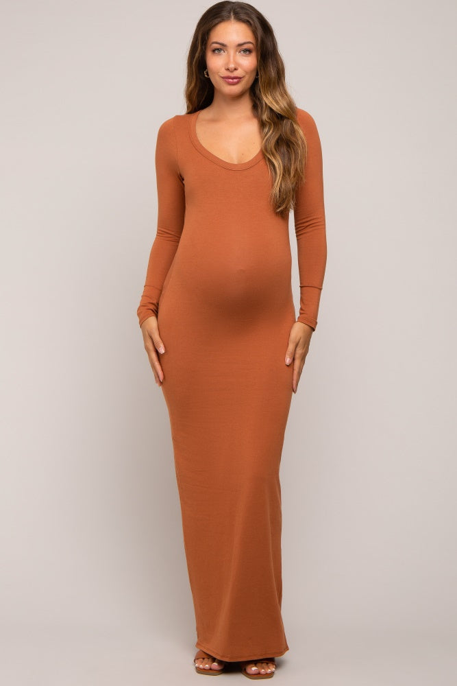 woman wearing a rust long sleeve maternity maxi dress, showing her baby bump