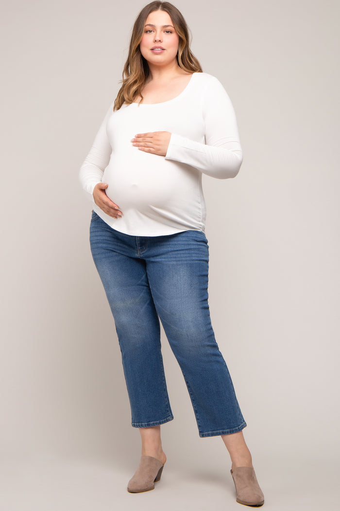 woman wearing a white long sleeve maternity top and blue cropped jeans, showing her baby bump
