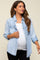 woman wearing a light denim maternity shirt over a white top and showing her baby bump