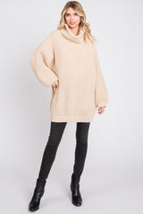 woman wearing an oversized beige ribbed sweater with a cowl neck paired with black skinny jeans and black ankle boots