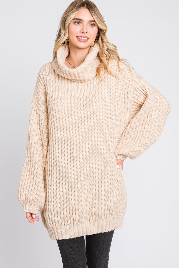 woman wearing a light beige oversized knit sweater with a cowl neck and long balloon sleeves