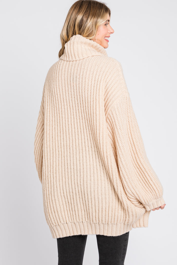 woman wearing a light beige oversized chunky knit sweater with a high collar and relaxed fit