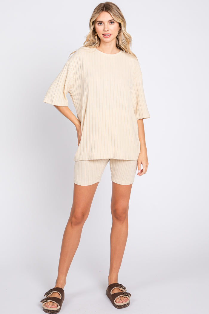 woman wearing a beige ribbed oversized t-shirt and matching bike shorts, styled with brown slide sandals