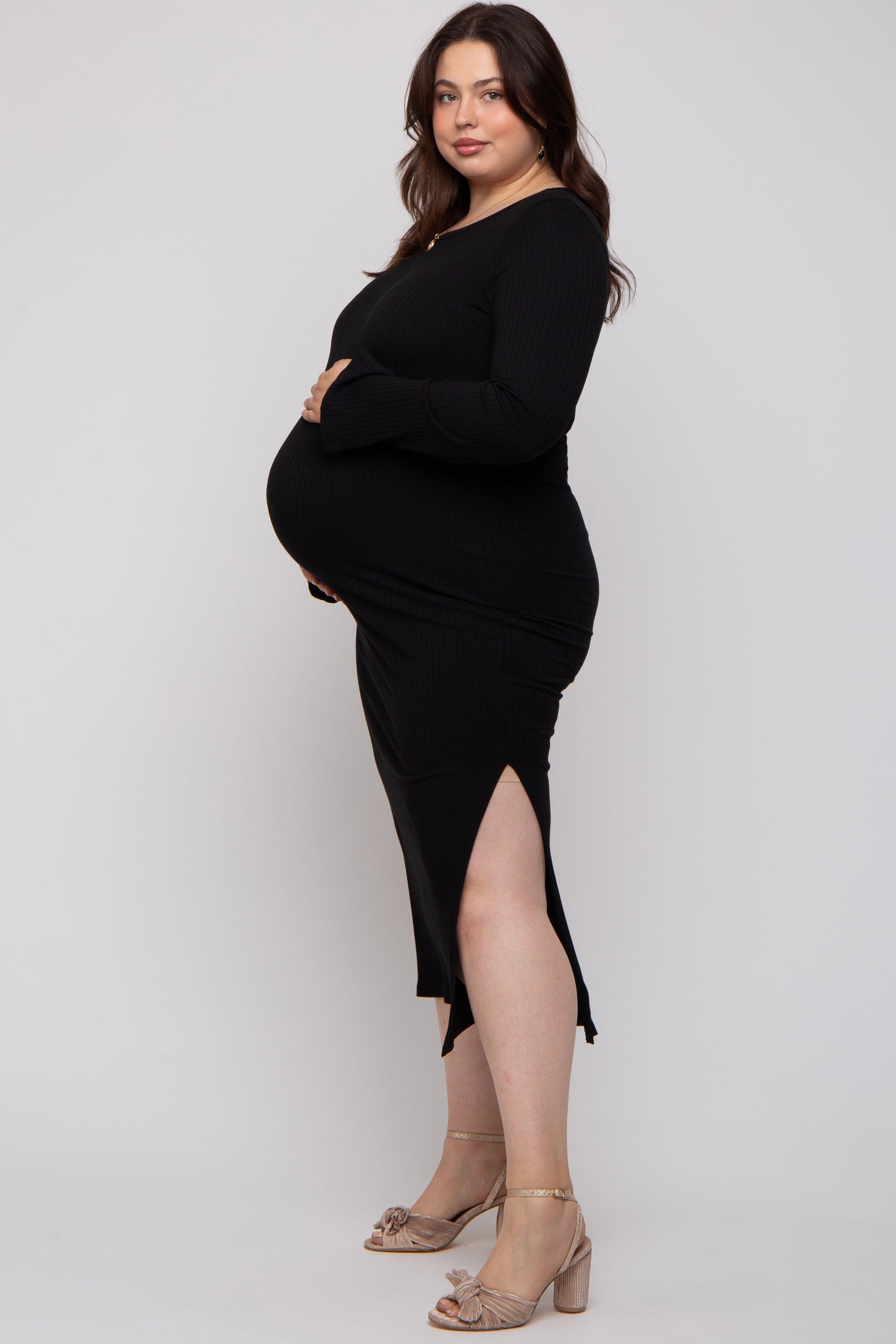 woman wearing a black ribbed maternity dress with a side slit, showing her baby bump