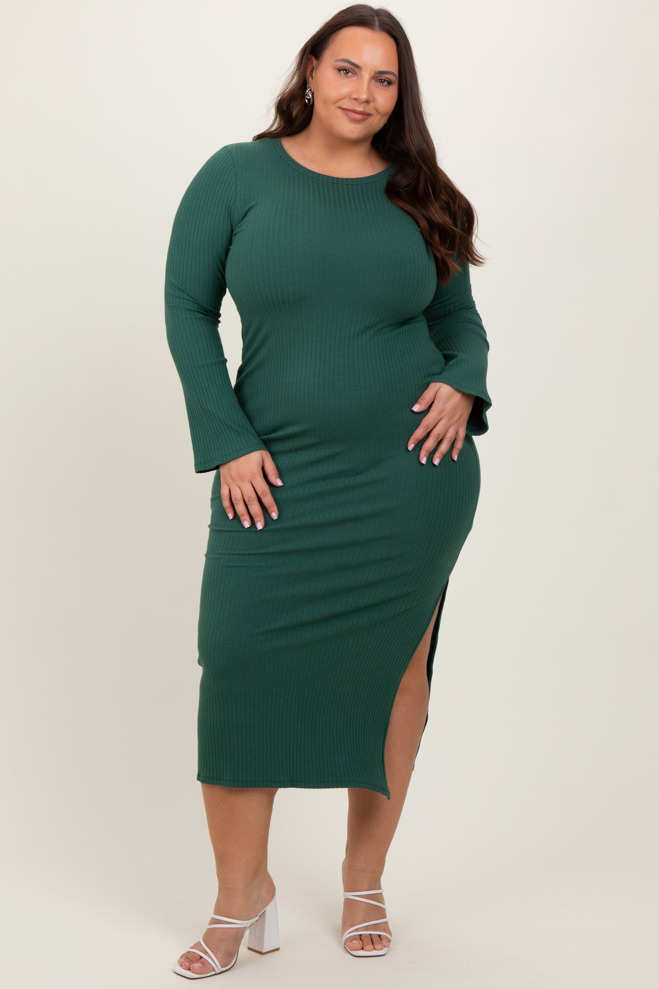 woman wearing a dark green ribbed long sleeve plus size dress with a side slit and her hand on her hip