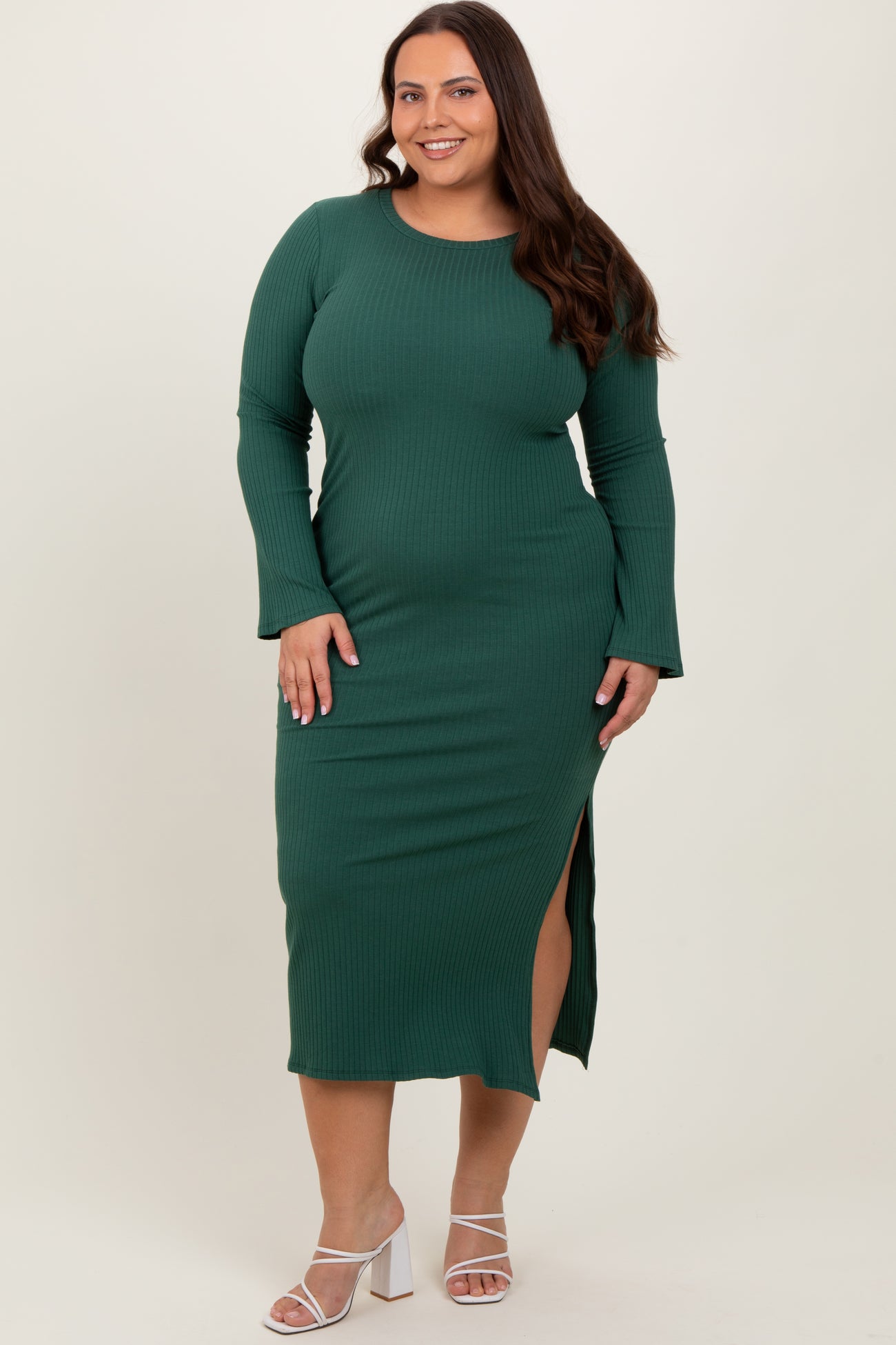 woman wearing a dark green ribbed plus size midi dress with long sleeves and a side slit