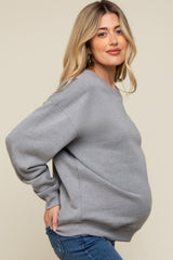 woman wearing a gray maternity sweatshirt and showing her baby bump