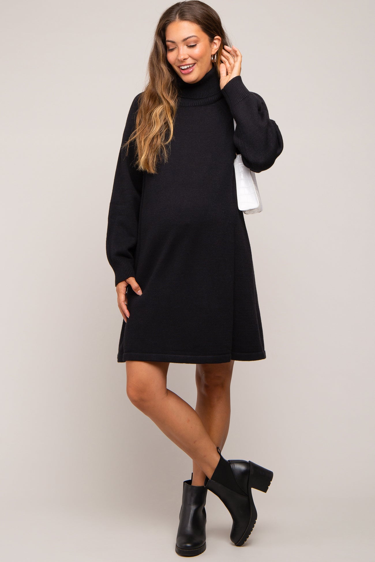 woman wearing a black maternity sweater dress with a turtleneck and long sleeves, showing her baby bump