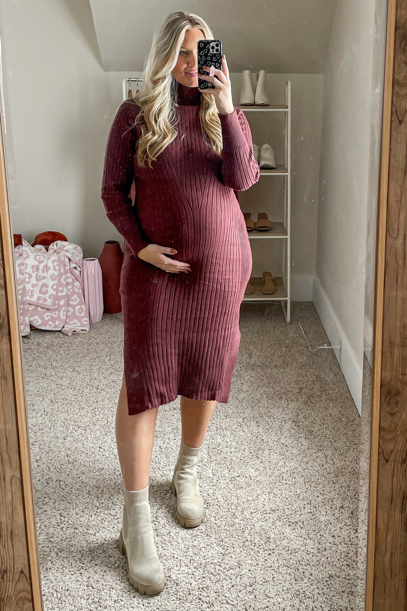 woman wearing a burgundy ribbed maternity dress and holding her baby bump in front of a mirror