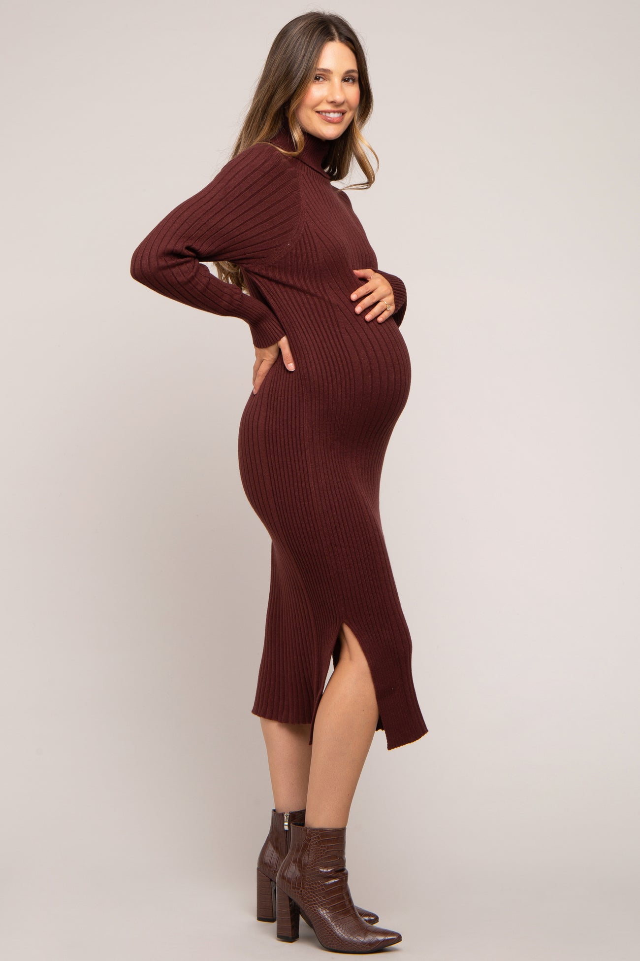 woman wearing a burgundy ribbed maternity dress with side slits and a visible baby bump